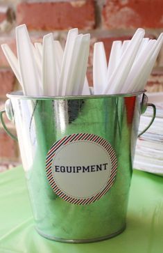 a green bucket filled with white sticks on top of a table