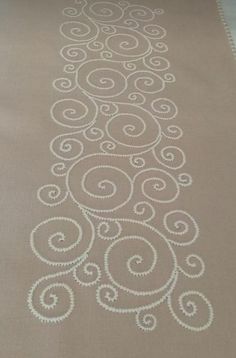 an embroidered table runner with white swirls on brown fabric, in the shape of a tree