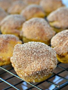 some sugar covered donuts are cooling on a wire rack in front of other doughnuts