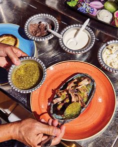 a person is dipping sauce on a plate with food in bowls around him and another bowl next to them