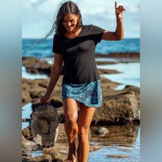 a woman is walking on the beach with her hat in one hand and sand in the other