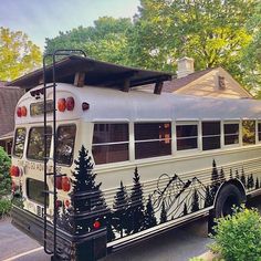 an old school bus painted with christmas trees on it's side is parked in front of a house