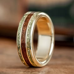 a wedding ring with wood and gold inlays on the inside, sitting on a table