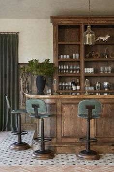 two bar stools sit in front of a wooden cabinet with glass doors and shelves