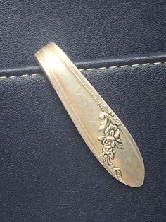 a silver spoon sitting on top of a blue piece of leather next to a white stitch