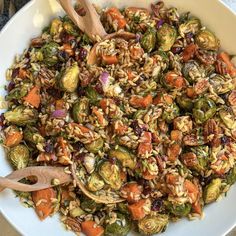 a white bowl filled with lots of food on top of a counter next to a wooden spoon