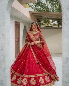 a woman in a red bridal gown posing for the camera with her hand on her hip