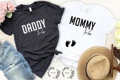 two t - shirts with the words daddy and mommy printed on them next to flowers