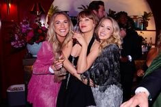 three women standing next to each other at a party