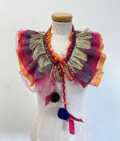 a white mannequin with multicolored scarves on it's neck