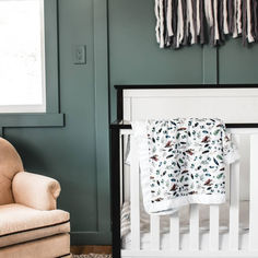 a baby's crib in a green room with a chair and blanket on the floor