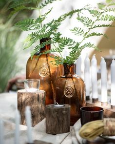 three brown vases sitting on top of a wooden table next to candles and plants