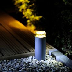 a blue cup sitting on top of a pile of rocks next to a wooden walkway