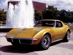 a yellow sports car parked in front of a fountain