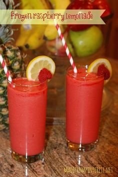 two glasses with strawberries and lemonade on a table next to pineapples