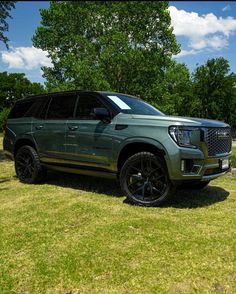 a green suv parked on top of a lush green field