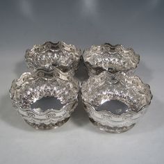 four silver dishes sitting next to each other on a table