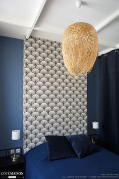 a bedroom with a blue bed and wallpaper that has circles on it, hanging from the ceiling