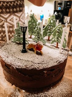 a chocolate cake with frosting and trees on top