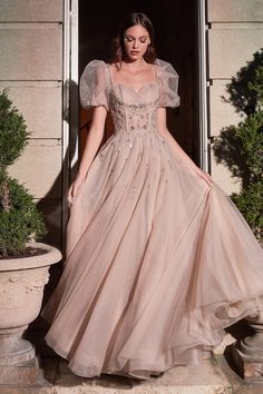 Dream the night away in this layered tulle ball gown. This champagne beauty is delicately beaded with a sheer puff sleeve and pleated bust cups to contour the bodice. Lace up the corset back for the perfect fit that leads up to a dainty back bow. Corset Gown With Sleeves, Bridgerton Gown, Grad Dinner, Bridgerton Vibes, Corset Dresses, Tulle Balls, Cinderella Divine, Dress Layered, Rose Champagne