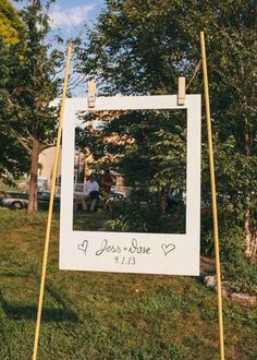 a sign that is sitting in the grass with a photo frame on top of it