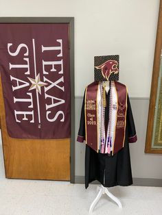 a graduation gown and stole are on display in front of a texas state flag banner