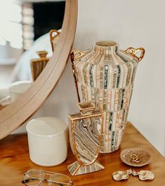 a vase sitting on top of a wooden table next to a mirror