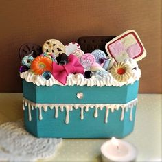 a blue box filled with lots of assorted items on top of a table next to a candle