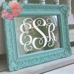 an ornate frame with the letter s on it and a flower sitting next to it