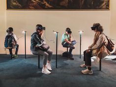 four people sitting on chairs with virtual headsets in front of them, all looking at their phones