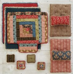 several different pieces of cloth on top of a wooden table with pillows and placemats