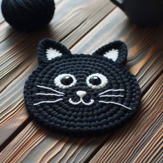 a crocheted black cat brooch sitting on top of a wooden table