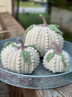 two knitted pumpkins sitting on top of a metal plate