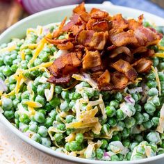 a bowl filled with peas and bacon on top of a table