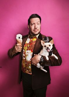 a man in a suit holding two small dogs and an ice cream cone on his shoulder