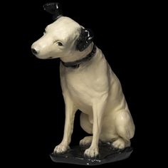 a statue of a dog sitting on top of a black surface with its head turned to the side