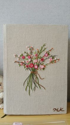 an embroidered book with pink flowers on it