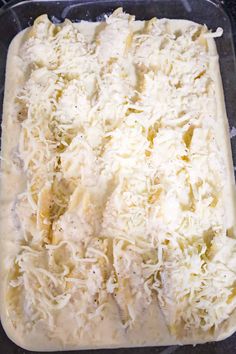 an uncooked casserole dish with cheese on top