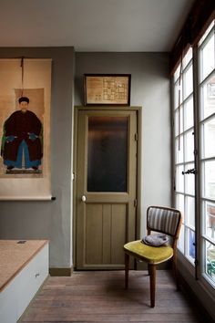 a yellow chair sitting in front of a doorway next to a painting on the wall