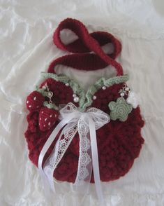 a crocheted red purse with white ribbon