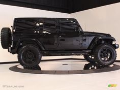 a black jeep is on display in a showroom with white walls and flooring