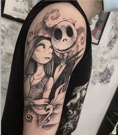 a person with a tattoo on their arm holding a jack skellingy face and an owl