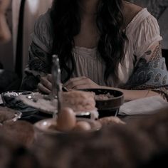 a woman sitting at a table with food in front of her and looking to the side