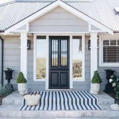 a black and white striped rug in front of a gray house with potted plants