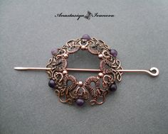 a brooch pin with purple beads and filigrees in the center on a gray background