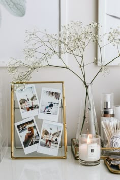 a white table topped with pictures and candles next to a vase filled with baby's breath