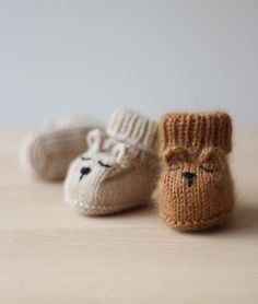 three knitted baby booties sitting on top of a wooden table next to each other