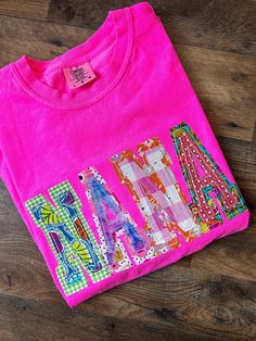 a pink t - shirt with the word love written in multicolored letters on it