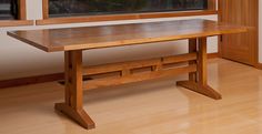 a wooden table sitting in front of a window on top of a hard wood floor