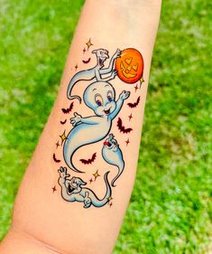 a person with a tattoo on their arm holding an orange ball in the shape of a ghost